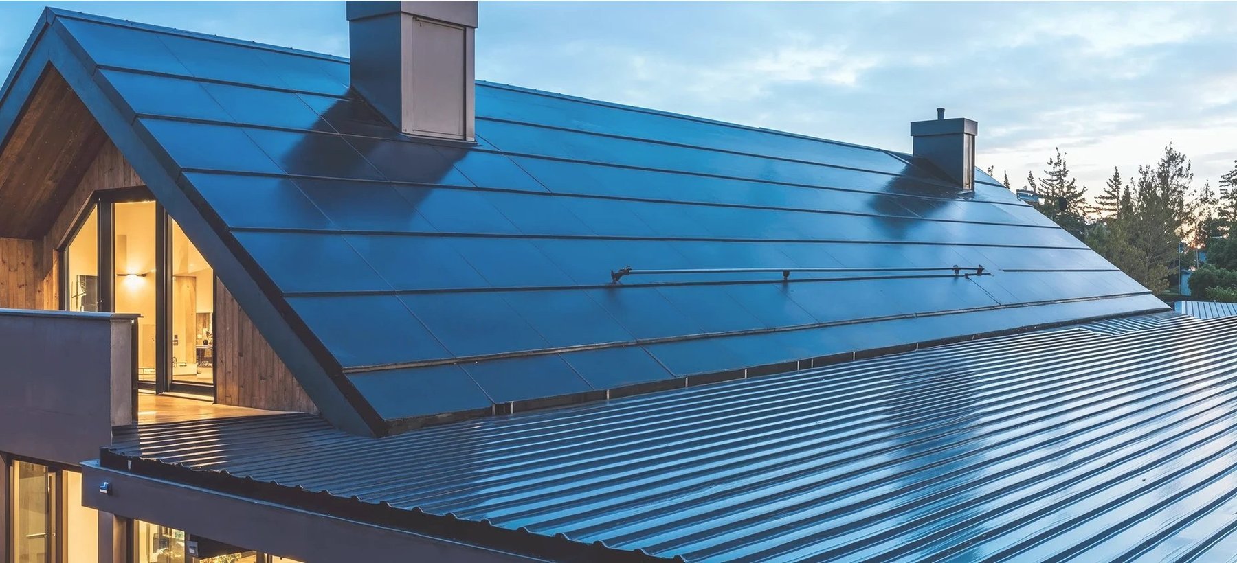A Quad+ roof plane at dusk beside a standing-seam metal roof